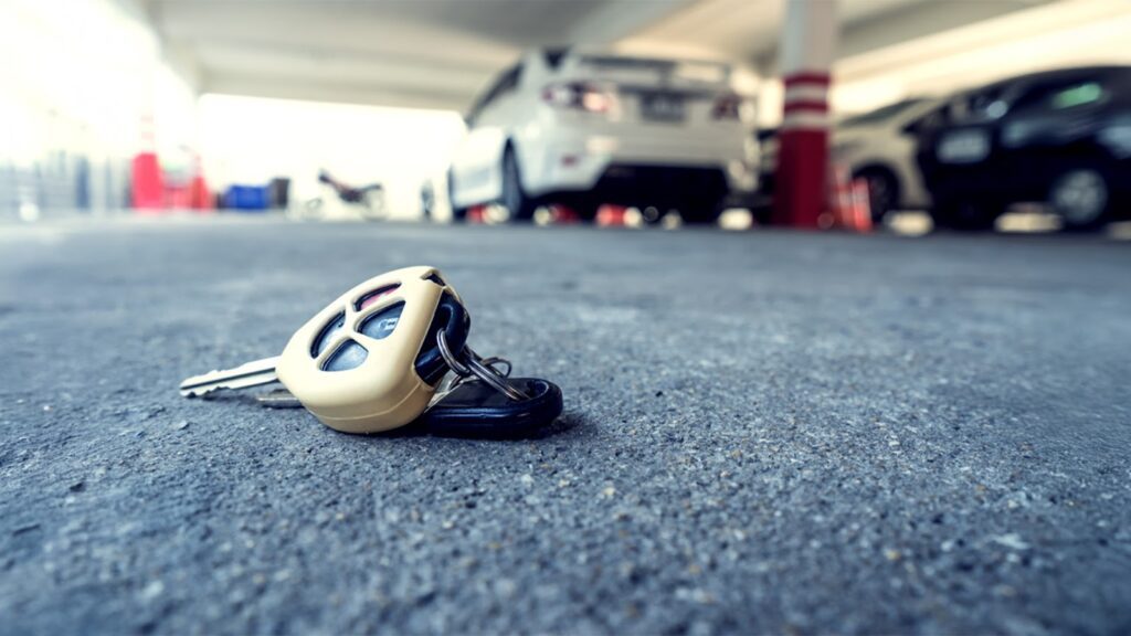 Image of dropped car keys in a parking lot with blurred cars in the background